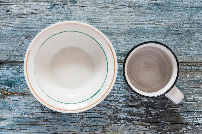 Empty plates and bowls on blue wooden background. Top view with copy space