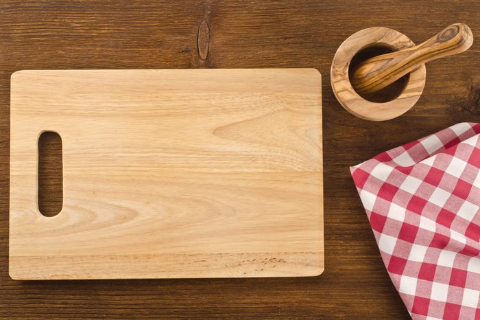 Cutting board with towel and bowl on wooden background