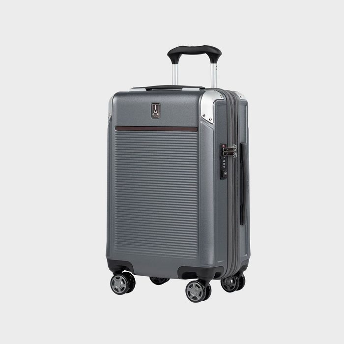 Gray suitcase stands upright with extended handle and wheels, featuring a ribbed design and lock system. Set against a plain, light background.