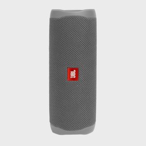 A cylindrical gray speaker, displaying a red JBL logo, stands upright against a plain, neutral background.