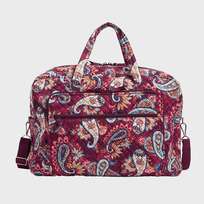Quilted paisley-patterned travel bag sits against a plain background, featuring a detachable shoulder strap, dual handles, and zippered pockets.