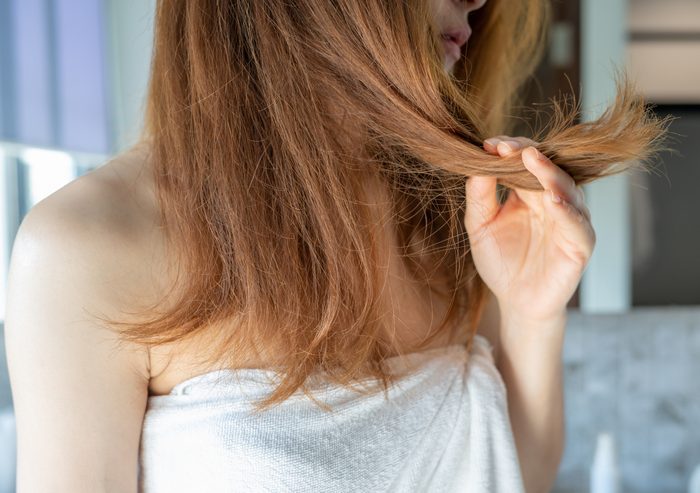 Cropped shot view of woman holding her damaged split ended and messy hair.