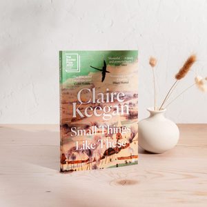 Book stands on wooden table; cover shows landscape with text: 