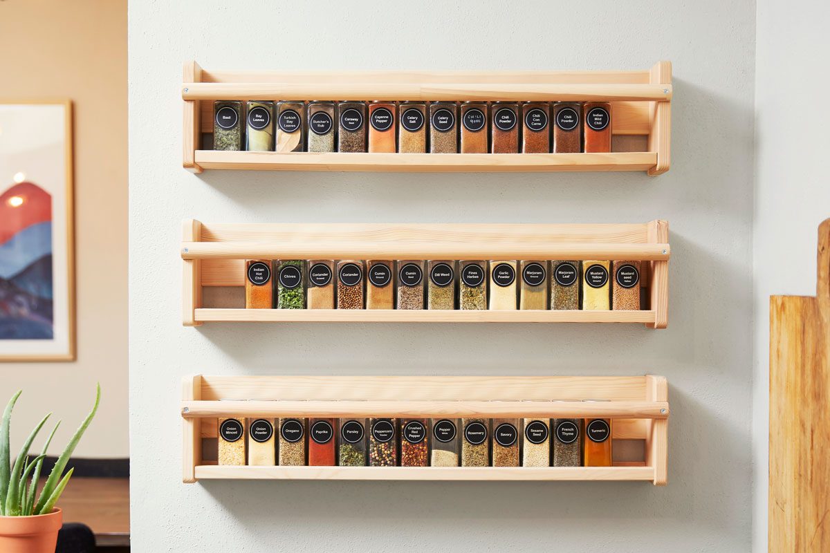 spices arranged alphabetically in wooden shelves on a white wall